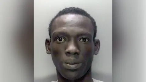 PA Media A mugshot Deng Majek, who is looking at the camera whilst in front of a grey background.