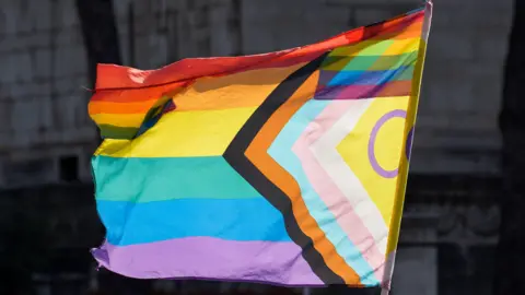 Getty Images Image of the progress pride flag. It has rainbow stripes and a triangle on the side.