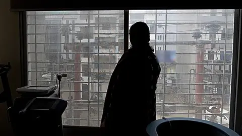 The silhouette of a woman standing by a window