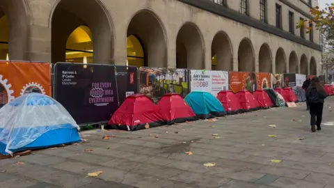 Alanah Hammond A line of tents of various colours outside Manchester town hall