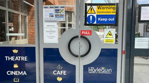 Julia Gregory/BBC The main entrance to the Harlequin Theatre in Redhill, showing a sign telling people to keep out due to it being a construction site.