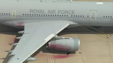 A grey plane with the words Royal Air Force written on the side of it. Red paint can be seen on parts of it.