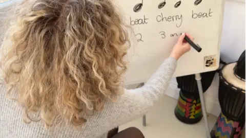 Teacher writing music notes on a white board.