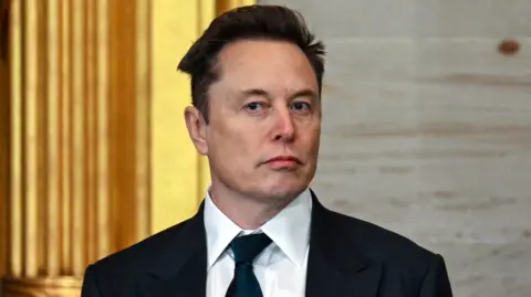 Getty Images Elon Musk wearing a sharp black suit and tie