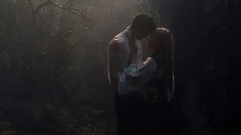 Warner Bros. Jacob Elordi and Margot Robbie as Heathcliff and Cathy, embracing in the rain in a scene from the film