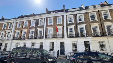 A row of residential two-story town houses on a London street can be seen, with the embassy at door number "40", along with the red flag of Montenegro