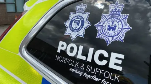 A close-up shot of a car window featuring both the Norfolk Police and Suffolk Police emblems