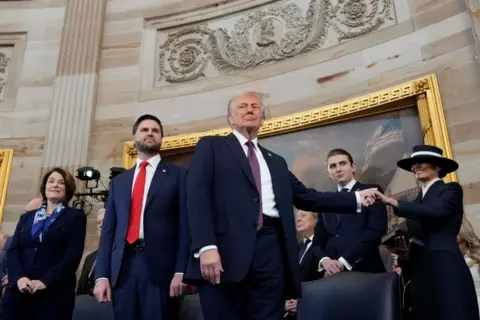 EPA President Donald Trump, center, holds the hand of his wife Melania Trump, far right, as their son Barron Trump, Vice President JD Vance, and Sen. Amy Klobuchar, D-Minn., far left, look on after taking the oath of office during the 60th Presidential Inauguration in the Rotunda of the U.S. Capitol in Washington, Monday, Jan. 20, 2025.