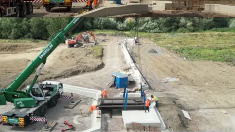 Swindon Borough Council A crane places a bridge on a stretch of dirt surrounded by workers in high-vis jackets.
