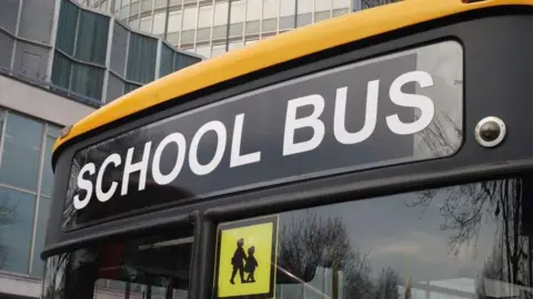 Getty Picture of the front of bus which says school bus and a school children sign just below at the top right corner of the window on the left