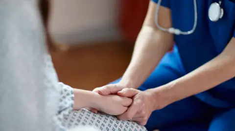 Cropped image of nurse in a blue uniform holding patient's hand - stock photo