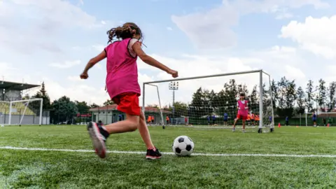Phynart Studios/Getty Children playing football