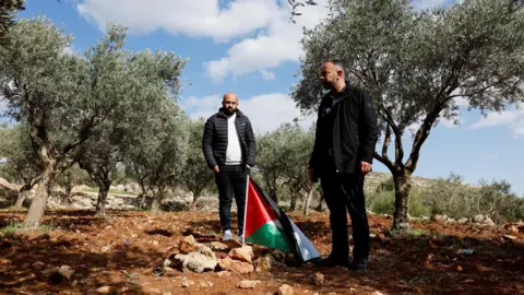Reuters Mousa and Omar Hamayel stand near bloodstains at the site where Thaer Hamayel was killed during an attack by Israeli settlers in the village of Abu Falah, near Ramallah, in the Israeli-occupied West Bank (9 March 2026)