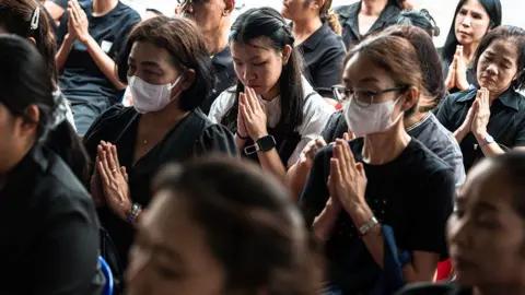 AFP via Getty Images Women praying, some wearing face masks
