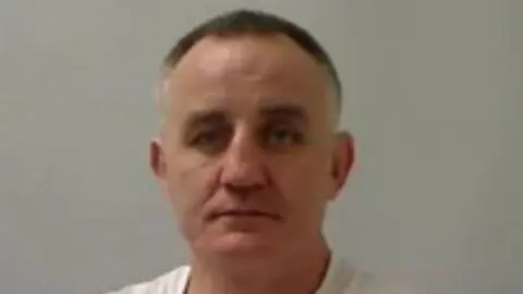 PSNI James Meehan in a white T-shirt. He has short black hair and greying at the sides. 