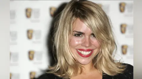 Billie Piper at the 2006 British Academy Awards smiling at the camera. She has blonde hair and red lipstick on. It is a head and shoulders shot of her.