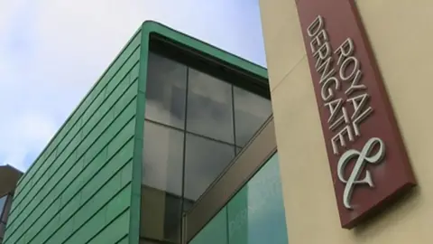 The exterior of Northampton Royal & Derngate's entrance on Swan Street. There is a sign written and printed vertically, reading ROYAL & DERNGATE.