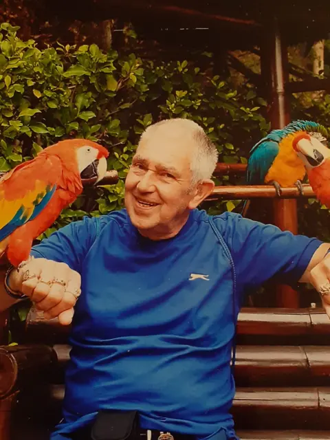 DAGCAS A man in a blue t-shirt with parrots on each arm