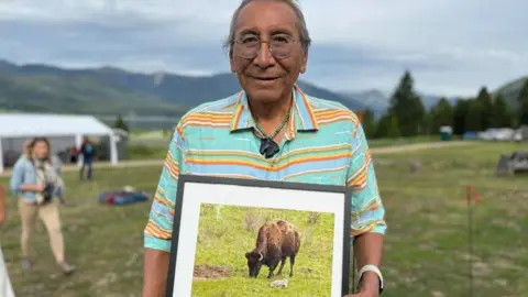 Buffalo Field Campaign Chief Looking Horse holds a photo of the white bison