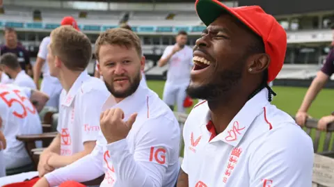 Jofra Archer, right, laughs while sat beside Ben Duckett, who is gesturing behind him
