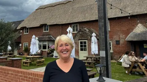 Deborah Risbridger Deborah Risbridger standing in front of The Elm Tree pub