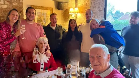 Family handout A photo of a Christmas gathering with a woman in the centre dressed in a Santa outfit and Lindsay Foreman wearing a pink sequined outfit