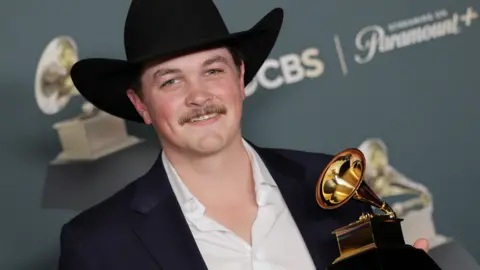 EPA/Shutterstock Zach Top pictured wearing a black cowboy hat while holding his Grammy Award trophy