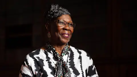 A woman in glasses and a blike and white top