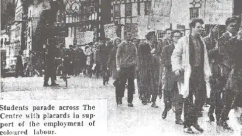 Bristol Evening Post A black-and-white newspaper cutting shows students marching in Bristol in protest against a "colour bar" on the buses. They're holding placards and walking in a large group