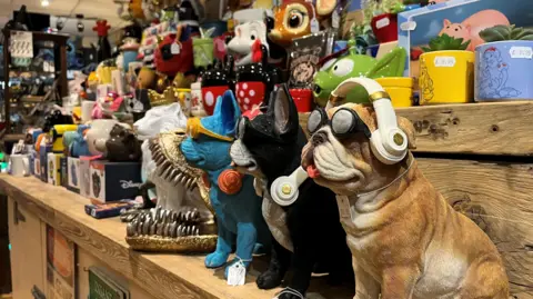 Animal figurines and colourful mugs with cartoon character on, on wooden shelves