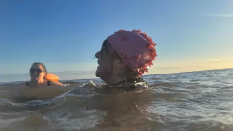 Amanda White Kate, wearing sunglasses, and Angie in her flowery pink swimming hat are members of the Hornsea Mermaids and are enjoying a dip in the North Sea 