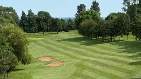 Mapperley Golf Club Open landscape of green of golf course. Lots of tall trees