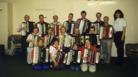 A line up of men and women holding accordions
