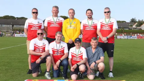 Muckle Media The original Orkney U16 football team standing in a group, with the Orkney flag at their feet