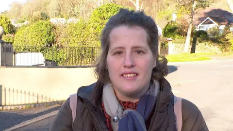 Mother Michelle Wheeler standing outside Combe Pafford School on a sunny day
