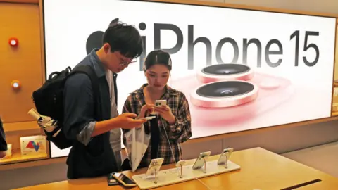 Woman and man look at iPhone 15 in Apple store