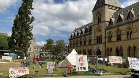 Fencing and placards outside pro-Palestine encampment, including "All Eyes on Rafah"