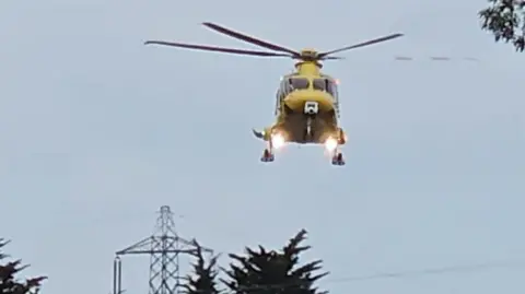 A helicopter hovering over the A30 in daylight.
