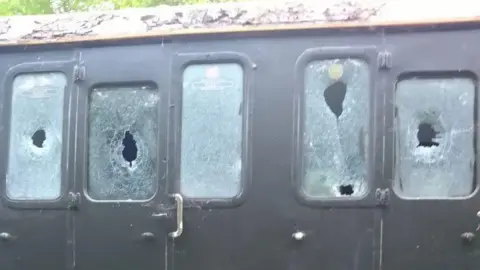 Close up of five smashed windows on a railway carriage on the Lavender Line.