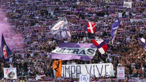 Getty Images A large crowd of Fiorentina fans, waving flags and holding scarves above their heads