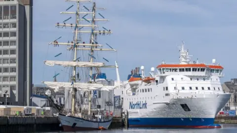 Tall ship in Aberdeen, with a white NorthLink ferry alongside, in Aberdeen harbour.