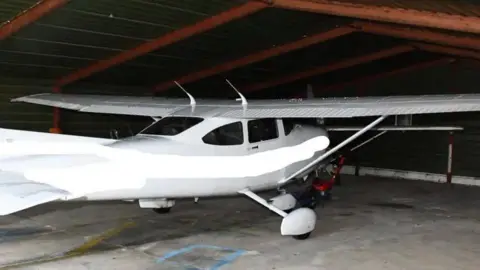 A white Cessna light aircraft pictured in a hangar 