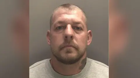 Merseyside Police Joshua Cropper looks astatine  the camera, with a leafage  tattoo connected  his neck, a situation  contented   grey sweatshirt, bluish  eyes, abbreviated  hairsbreadth  and a beard. 