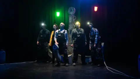 Joseph Lynn Four fishermen and a woman on stage. Three of the men wear lamps on their heads.