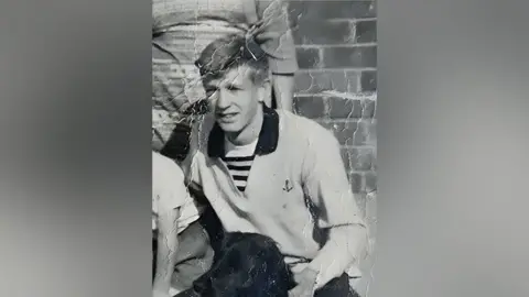 David Lawrence David Lawrence wearing a polo shirt in a black and white photo, sitting behind a dog