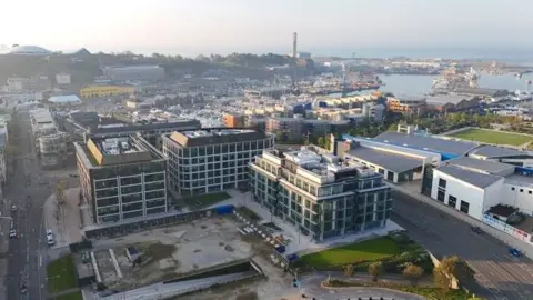 Aerial view of Jersey’s waterfront showing modern office buildings and harbour in the background.
