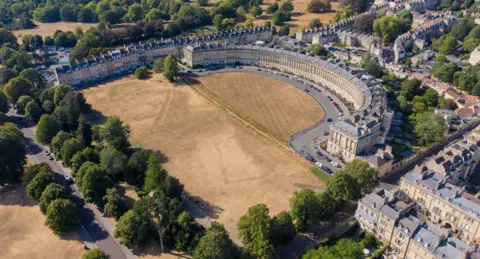 Getty Images/Anna Barclay An aerial view of the Royal Crescent in Bath showing a severely dry and brown lawn in front. There are lots of trees in leaf - showing very green against the colour of the grass