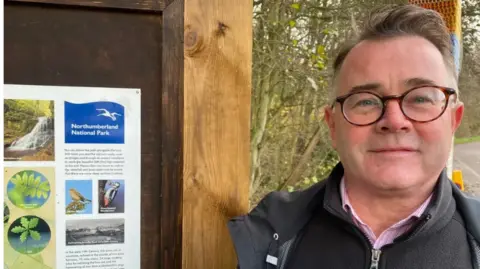 Tony Gates standing in front of a poster for the national Park 