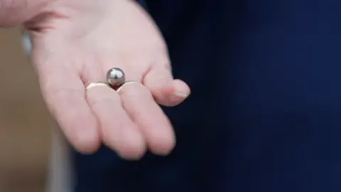 Ben Moore/BBC Barbera Servante holding the ball bearing that was shot through her window.