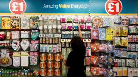 Reuters A woman stands in front of a display of baby and party products at Poundland.